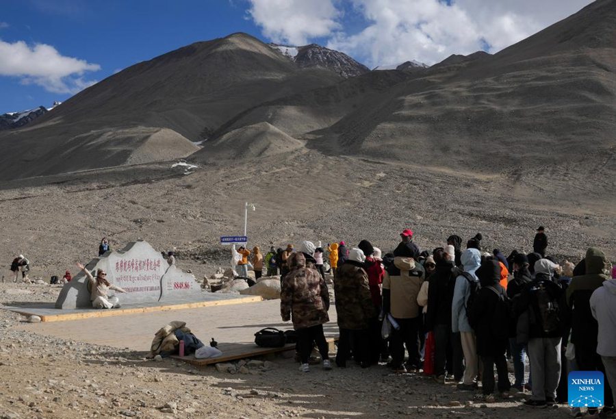 Turisti in fila per scattare foto ai piedi del Monte Qomolangma, nella Regione Autonoma dello Xizang, nel sud-ovest della Cina. (24 maggio 2024 – Xinhua/Ding Ting)