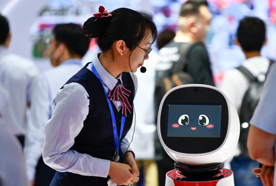 Un membro dello staff interagisce con un robot al quinto World Intelligence Congress presso il Tianjin Meijiang Conference and Exhibition Center, nella Cina settentrionale. (23 maggio 2021 - Xinhua/Sun Fanyue)