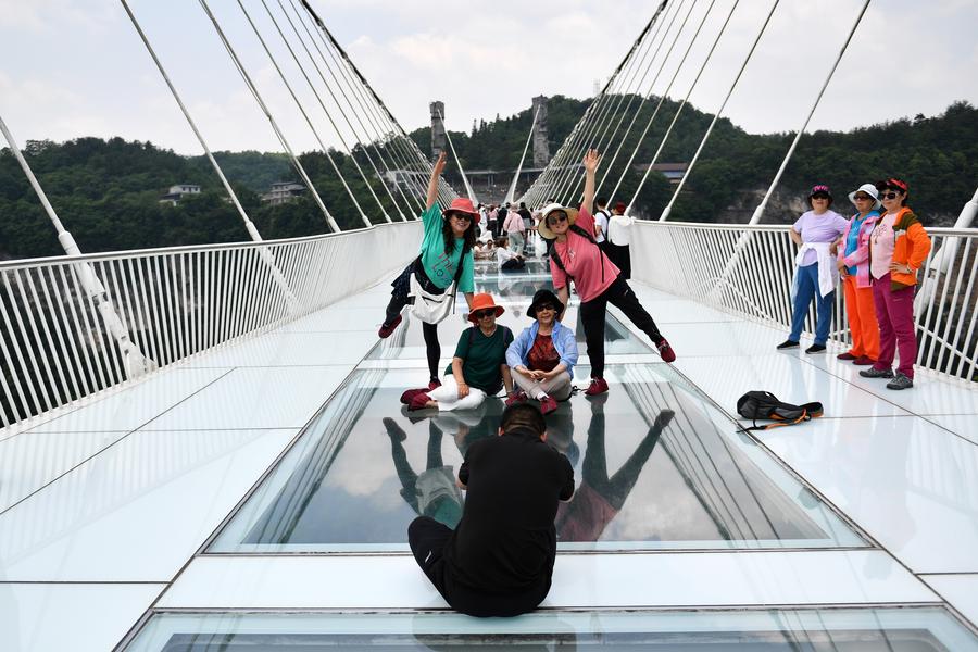 Turisti della Repubblica di Corea posano per delle foto su un ponte con pavimento di vetro nel Grand Canyon di Zhangjiajie, nella provincia centrale cinese dello Hunan. (23 maggio 2024 - Xinhua/Chen Zhenhai)